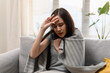 © pitipat - Young Asian woman caught a cold and high fever headache symptom when stay at home alone. Asia Urban lifestyle healthcare concept.
