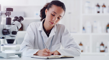 Wall Mural - investigating one matter after another. shot of a young scientist writing notes while working in a l
