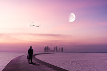 A Lonely Man Is Standing On A Wooden Pier And Looking To The Horizon With Lilac Sky And Moon