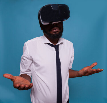 Portrait of confused man wearing virtual reality goggles trying to understand how to use modern digital technology. Person with vr headset in 3d simulation having disappointing experience.