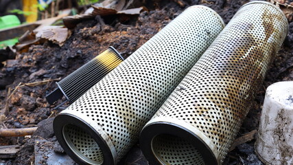 Wall Mural - Dirty old oil filter waste. Old, used oil filters are left on the outdoor ground as an improper disposal of hazardous waste with a copy space. Close-up focus