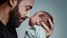 Portrait Of Man Looking At His Newborn Son With Loving Expression