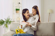 © Studio Romantic - Caring small teen girl child make surprise to excited young mom congratulate with mothers day. Loving little daughter greeting mum give present and flowers to happy parent. Gratitude concept.