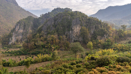 Wall Mural - Beautiful landscape view of scenic limestone mountain with mango orchard in foreground in rural agricultural valley near Chiang Dao, Chiang Mai, Thailand