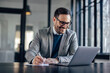 © bnenin - Smiling caucasian man, writing on a piece of paper, looking at the laptop.