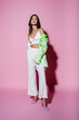 © LIGHTFIELD STUDIOS - full length of young woman in blazer and white pants standing on pink