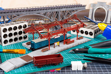 Construction Of Model Railroad Layout. Workbench With Model Railway Train Station Bridge Tracks And Landscape Tools. Hobby Leisure Scale Modelling Concept