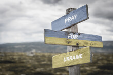 Pray For Ukraine Text Quote On Wooden Signpost Outdoors, Written On The Ukranian Flag.