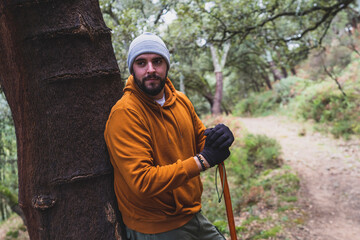 Chico alto con barba y ataviado con equipo de senderismo realizando ruta verde en un pico de la sierra malagueña 