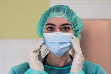 The female animal surgeon or veterinarian puts on a medical face mask. Doctor is preparing for surgery in the operation room. Medicine and healthcare