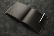 Blank black book and pen on black stone background. Template for placing your design.