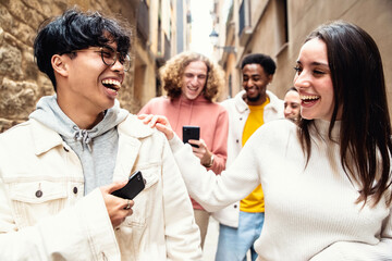 Wall Mural - Multiracial friends hanging out in city center together - Happy different guys and girls watching smart mobile phones walking outside in the street - Modern lifestyle and real youth life concept