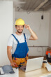 © Kostiantyn - Smiling handyman worker in uniform wearing tool belt and hardhat looking at camera during renovation work indoors