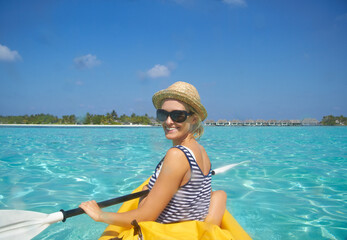 Paddling towards the beach. A beautiful young woman paddling on a boat in a tropical ocean.