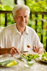 Handsome senior man eating healthy breakfast outdoors