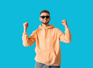 Wall Mural - Happy young guy in stylish hoodie on color background