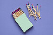 Box with different new matchsticks on purple background