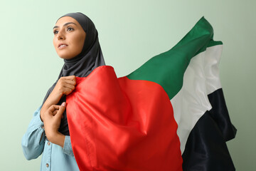 Poster - Beautiful Muslim woman with waving UAE flag on green background