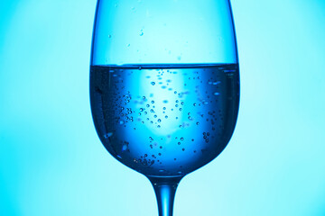 Glass of clear water on blue background