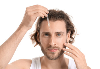 Young man using serum for skin care on white background