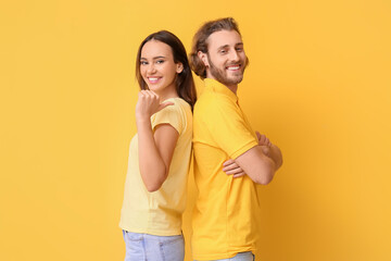Wall Mural - Young couple in stylish t-shirts on yellow background