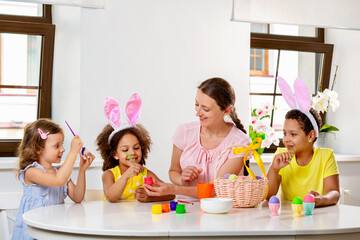 Wall Mural - Family paints eggs for Easter holiday sitting at the table