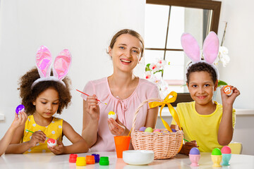 Wall Mural - Family paints eggs for Easter holiday sitting at the table