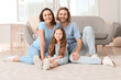 © Pixel-Shot - Young family sitting on soft carpet at home