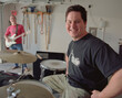 © SuperStock - Portrait of middle aged male drummer in garage band