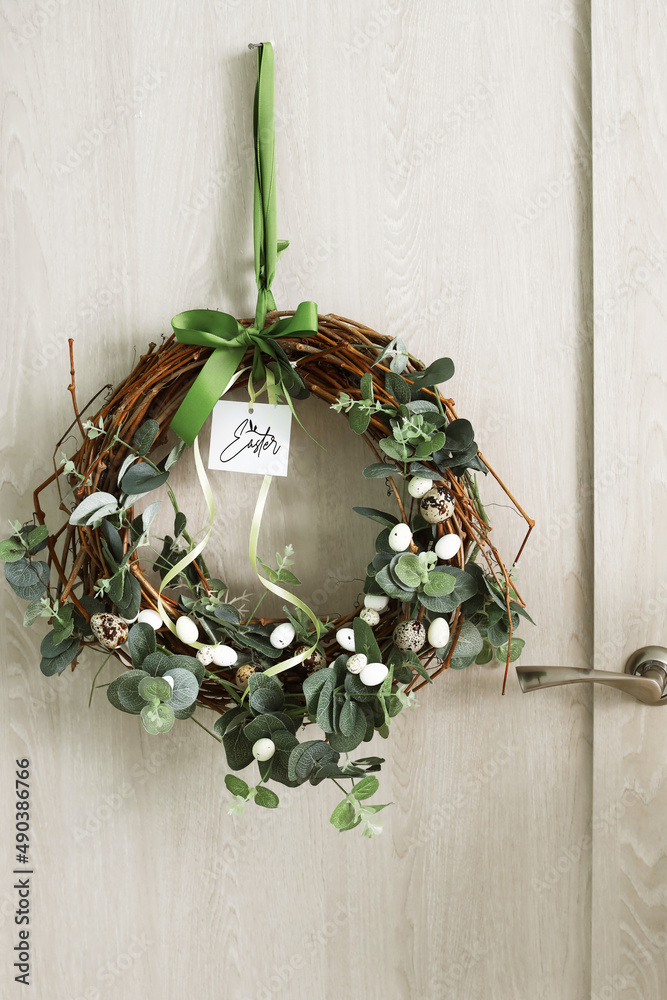 Door with beautiful Easter wreath and greeting card