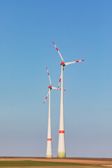 Wall Mural - Two wind turbines dominate nature, upright image