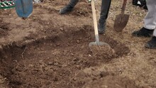 Freshly Dug Grave Tool At Cemetery, A Close-up. Grave, Top View, Just Been Digged, Spade By Edge. Digging. Pit In Ground. Shovel Lies In Pit. Digging Hole With Spade In Field