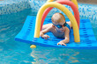 © ninelutsk - Toddler child crawling through tunnel on the water. Kid playing and learning to swim dive with equipment and toys in swimming pool in goggles. Boy doing early physicals development activities