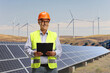 © Ljupco Smokovski - Mature engineer standing on a wind turbine farm with solar panels