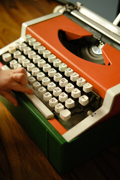 Children's hand presses space bar on orange vintage typewriter and wants to make pause. Child learns letters. 