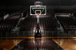 © SuperStock - Empty basketball arena with dramatic lighting, view from free throw line in front of goal on the court