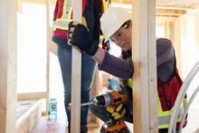 Female Construction Using Power Drill On Construction Frame