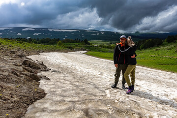 A girl with a man on a glacier on the snowy plateau of Lagonaki in Adygea. Russia. 2021.