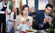 Portrait of satisfied man and woman in the restaurant with mobile phones