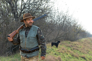 Wall Mural - Hunter man in camouflage with a gun during the hunt in search of wild birds or game. Autumn hunting season.