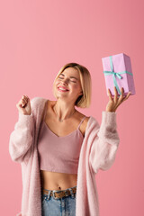 Canvas Print - happy young woman with closed eyes holding wrapped gift box isolated on pink.