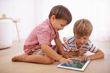 Canvas Print - Showing him some tablet tricks. Shot of little boys playing on the floor.