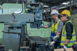 © Jack Tamrong - Engineer and assistance in safety uniforms working with heavy machine in machinary factory