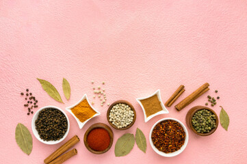 Wall Mural - Spices and seasonings in small bowls on pink background, space for text