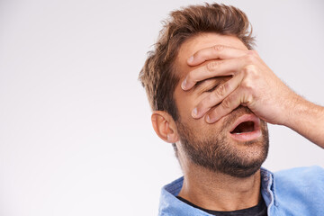 Poster - Oh no. Studio shot of a handsome young man covering his eyes in regret against a gray background.