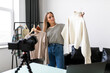 Fashion blogger woman in jeans and turtleneck showing casual colorful shirts on camera. Stylist influencer girl showing trendy clothes filming vlog episode for her channel. Opinion leader sets trends.