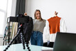 © F8  \ Suport Ukraine - Fashion blogger woman in jeans and turtleneck showing casual colorful shirts on camera. Stylist influencer girl showing trendy clothes filming vlog episode for her channel. Opinion leader sets trends.
