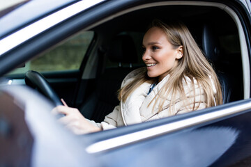 Young woman driver sitting in car, driving in the street