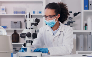 investigating the world through science. shot of a young scientist using a microscope in a lab.