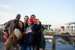 © StratfordProductions - Multi-cultural group of friends taking a selfie at a rooftop party. Attractive young adult friends, posing for camera.